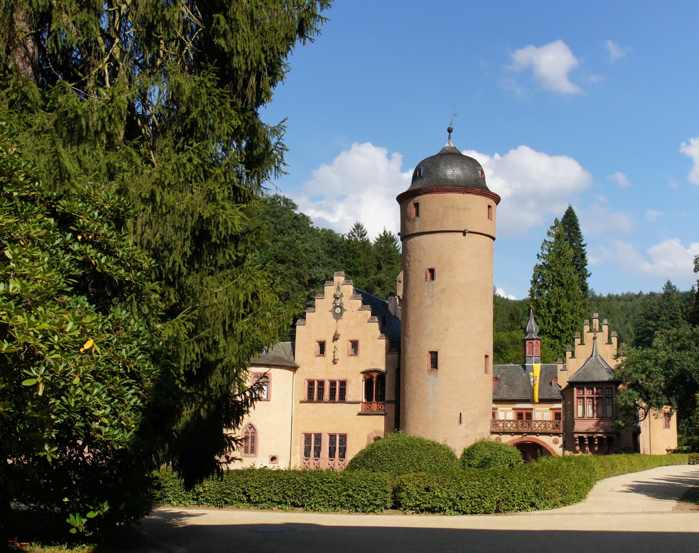 Das Wasserschloss Mespelbrunn mit rundem Turm hinter Bäumen Das Wasserschloss Mespelbrunn mit rundem Turm hinter Bäumen